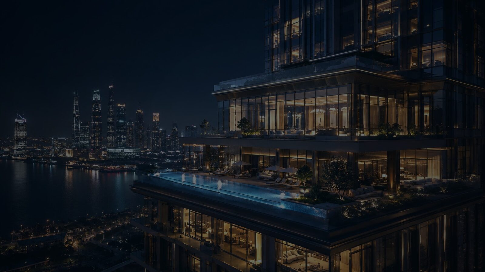 Illuminated skyscraper with a rooftop infinity pool over a city harbour
