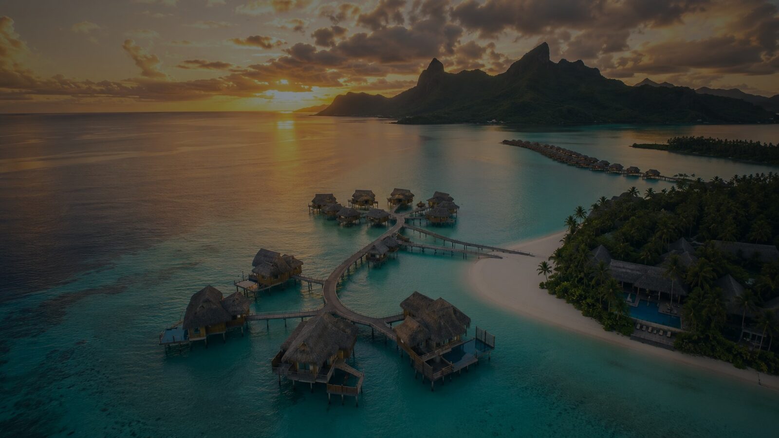 Overwater villas at a tropical destination resort at sunset